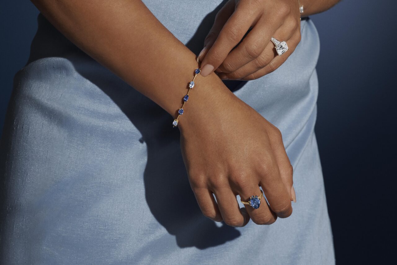 Model in blue wearing a sapphire bracelet and rings from the Elizabeth Taylor Collection